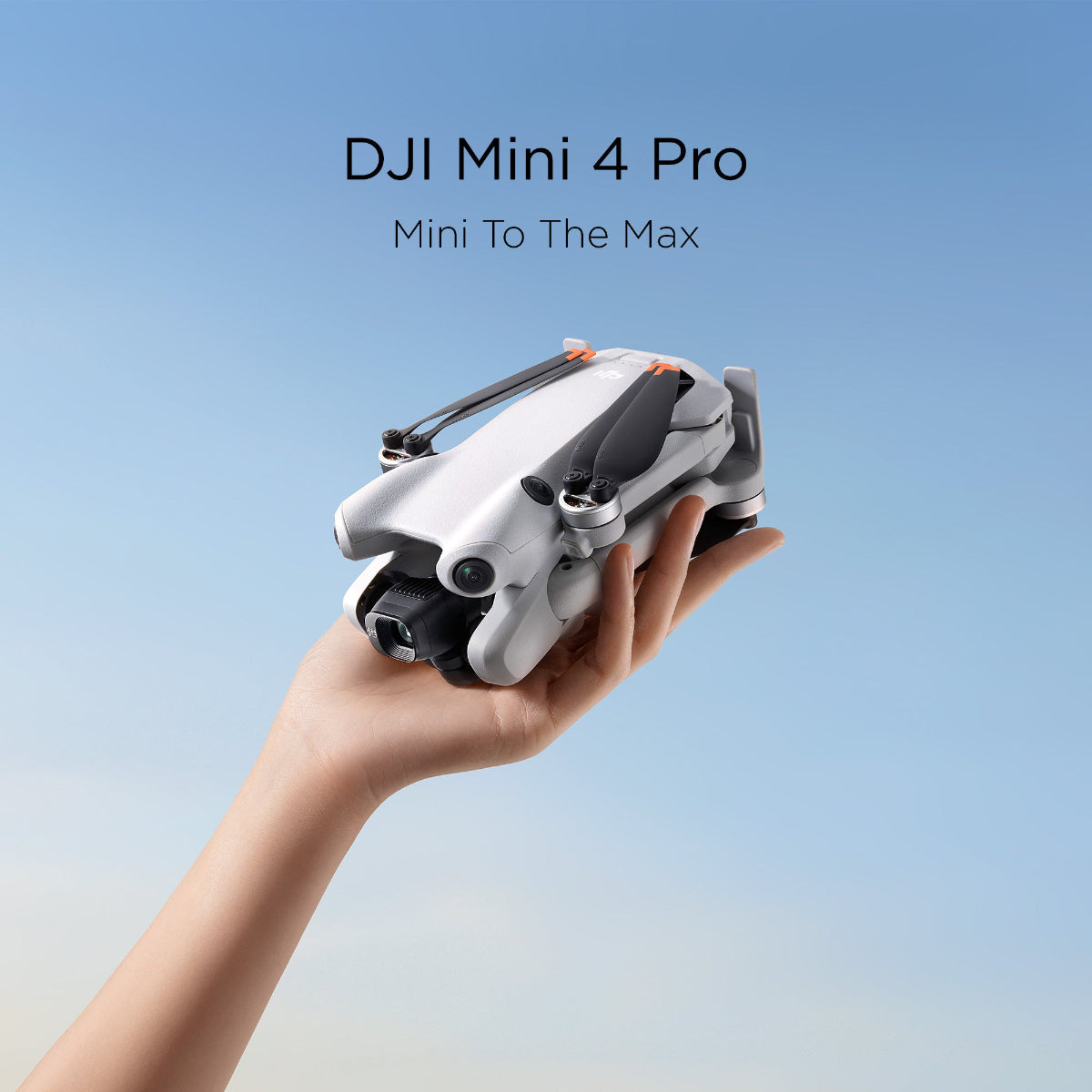 DJI Mini 4 Pro drone held in a hand against a blue background.