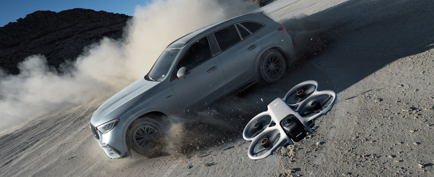 A DJI Avata 360 flies over a moving vehicle in this still shot.
